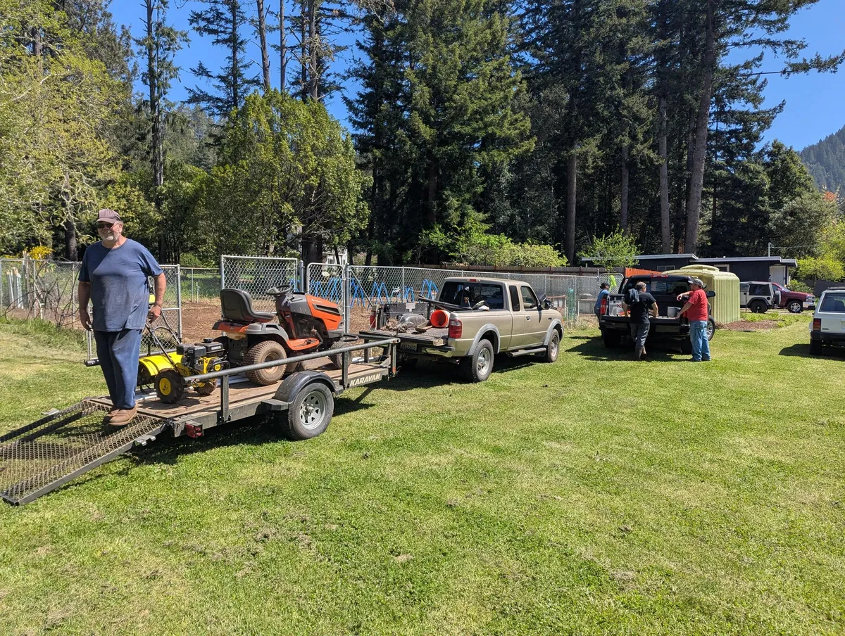 People working outside the church near a utility trailer and gardening equipment.