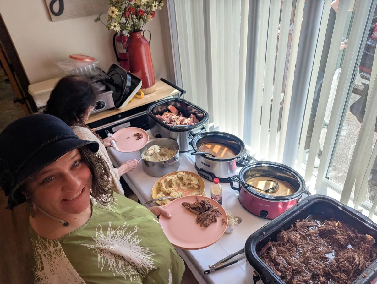 People serving themselves food from a buffet at a gathering.